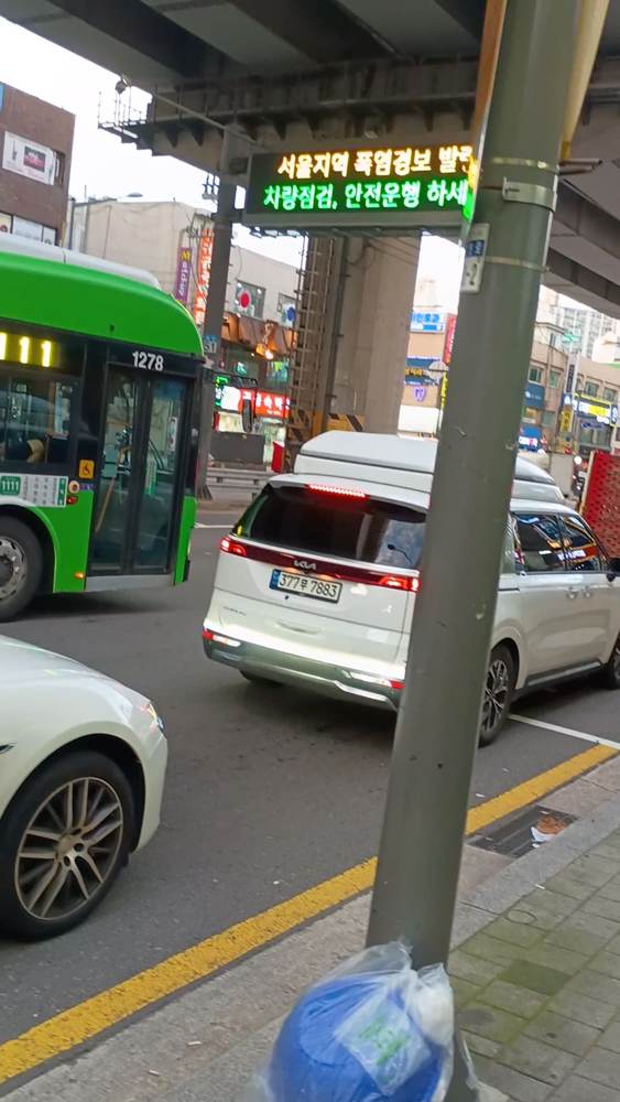 정차 중인 버스 옆으로 차량들이 연속해서 지나가는 장면